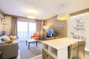 Una cocina y una sala de estar con una mesa y una sala de estar. en MERIBEL Appartement Neuf Résidence Hevana, en Méribel