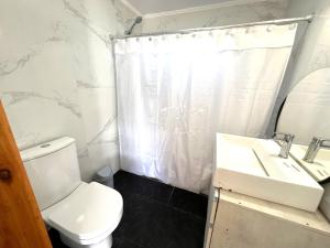 a white bathroom with a toilet and a sink at Alquiler Mar del Plata Casa en Acantilados in Mar del Plata