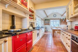 a large kitchen with red cabinets and a table at Beautiful Country House with Forest View & Garden in Norleywood