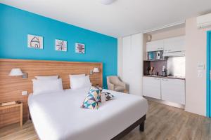 een slaapkamer met een groot wit bed en een blauwe muur bij Appart’City Confort Vannes in Vannes