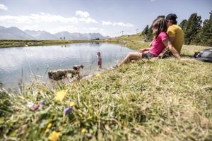 a group of people sitting next to a river with a dog at Chalet Andreashof in Gerlos