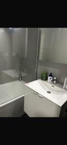 a white bathroom with a tub and a sink at Appartement Donatella in Liège