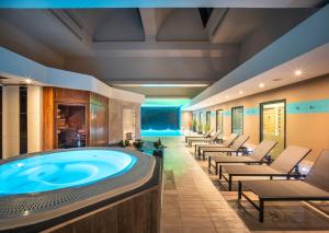 ル・アーヴルにあるHotel Spa Le Pasinoのホットタブ、ラウンジチェアが備わる広い客室です。