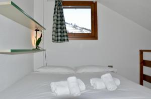 - un lit blanc avec trois oreillers et une fenêtre dans l'établissement Hostdomus - Casa Borgata, à Borgata Sestriere