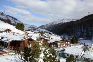un village recouvert de neige avec des montagnes en arrière-plan dans l'établissement Hostdomus - Casa Borgata, à Borgata Sestriere