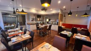 a restaurant with tables and chairs and a kitchen at Logis - Le Christina in Bourges