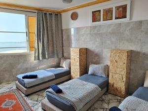 a bedroom with two beds and a couch and a window at Swet Surf Hostel in Taghazout