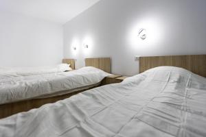 two beds in a room with white sheets at Pensiunea Arieș in Craiova