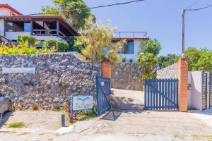 a house with a blue gate and a stone wall at La Proeza Pousada in Búzios