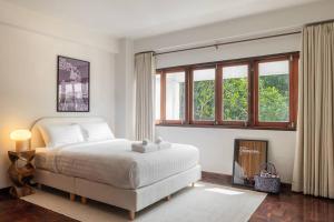 een slaapkamer met een groot wit bed en ramen bij Timber & Terrace in Bangkok +38 foto's