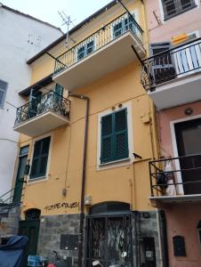 a yellow building with green doors and balconies at Appartamento dietro il lungomare fra le due baie, fino a 8 posti letto in Sestri Levante +34 photos