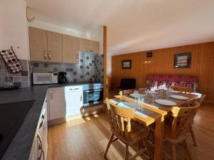 a kitchen with a wooden table and chairs in a kitchen at Résidence Atrey Clés Blanches in La Tania