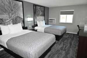 ein Hotelzimmer mit zwei Betten und einem Fenster in der Unterkunft Super 8 by Wyndham Higginsville in Higginsville