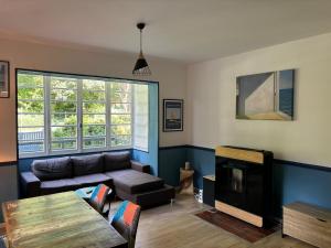 a living room with a couch and a tv at Les Fougères - Bois de Cise in Ault