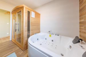 a bathroom with a large white tub and a shower at Les 4 Saisons des Violonges - Vue montagne in Neussargues en Pinatelle