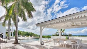 a patio with a table and chairs and a pool at Stunning 6BR Villa Near Longue Bay Beach in Baie Longue