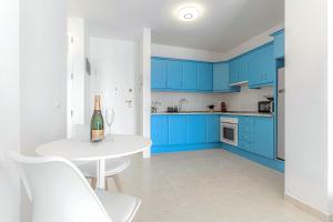 a kitchen with blue cabinets and a white table with a bottle of wine at Blue apartment with One bedroom, WiFi and amazing view in Chayofa