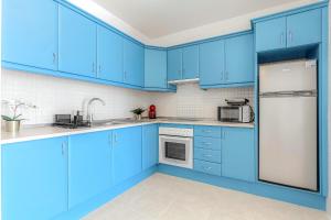 a blue kitchen with white appliances and blue cabinets at Blue apartment with One bedroom, WiFi and amazing view in Chayofa