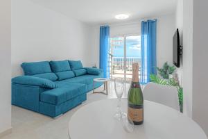a living room with a blue couch and a wine bottle on a table at Blue apartment with One bedroom, WiFi and amazing view in Chayofa