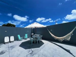 eine Terrasse mit Tisch und Stühlen und einem Sonnenschirm in der Unterkunft ParkMar III - São José, Maragogi in São José da Coroa Grande