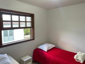 a bedroom with a red bed and a window at Residencial Vista da Serra in Diamantina