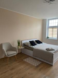 a bedroom with a bed and a chair and a window at City Lights Apartament in Barlinek