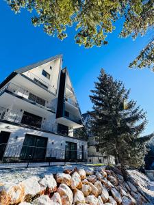 a building with a tree in front of it at Harmony Peak Jahorina in Jahorina