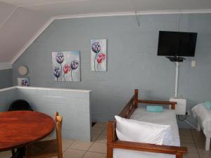 a room with a bed and a table and a tv at Crow's Nest Self-Catering Accommodation in Saldanha