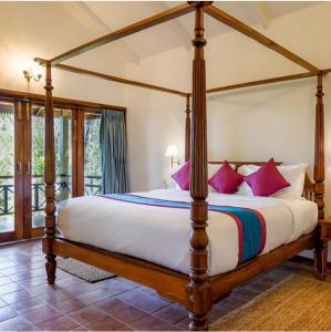 a bedroom with a four poster bed with pink pillows at Wild Heritage Desert Camp in Jaisalmer