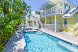 a pool in front of a yellow house with palm trees at Andy's Attic in Key West +15 photos