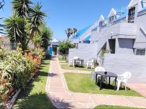a patio with tables and chairs in front of a building at Crow's Nest Self-Catering Accommodation in Saldanha
