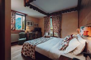 a bedroom with a bed and a desk and windows at Villa Novecento Romantic Hotel - Estella Hotel Collection & Experience in Courmayeur
