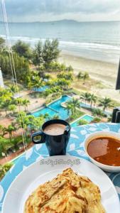 a table with a plate of food and a cup of coffee at Sea View & Pool View & WiFi & Netflix at Iman Kazoku TimurBay Ville Studio 2BDR in Kuantan