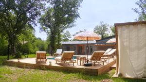 a wooden deck with chairs and an umbrella at Maison avec terrasse en bois et piscine in Varaire