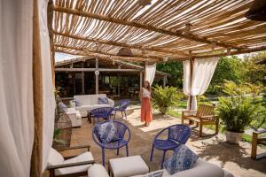 a woman standing under a pergola with chairs and tables at Vila Capininga Ecopousada in Santo Amaro