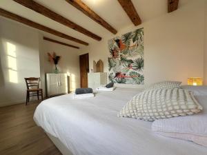 a bedroom with a large white bed with a painting on the wall at Les 7 Prunes - Demeure Alsacienne d'Exception in Zellwiller