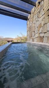 een zwembad met water naast een stenen muur bij Vila Baru in Alto Paraíso de Goiás