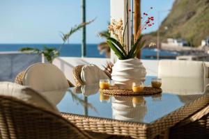 a glass table with chairs and a vase with candles at Sunset house in Paul do Mar