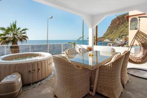 a balcony with a hot tub and a table and chairs at Sunset house in Paul do Mar