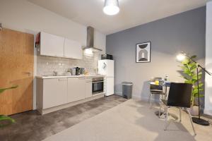 eine Küche mit weißen Geräten sowie einem Tisch und Stühlen in der Unterkunft Vibrant 1 Bed Apartment, FREE Parking, North Church St, Sheffield City Centre - Hosted by Stay Host Save in Midland + 14 Fotos