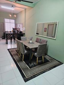 a dining room with a table and chairs on a rug at Syahar Homestay Temerloh in Temerloh