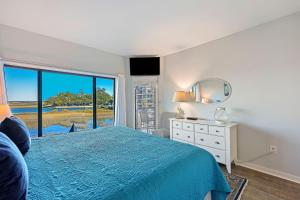 une chambre avec un lit bleu et une grande fenêtre dans l'établissement 245 Captains Quarters, à Île de Hilton-Head 37 autres photos