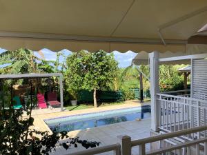 a house with a swimming pool and an umbrella at VILLA ALIZÉE Logement 3 in Sainte-Rose