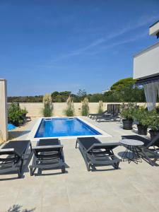 a swimming pool with chaise lounge chairs and a table at Rimac Apartments in Novalja
