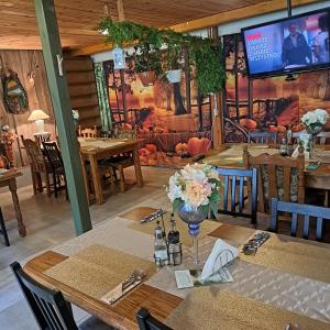 a dining room with a table with flowers and a tv at Dom myśliwski in Mosty