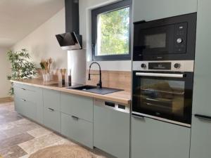 a kitchen with a microwave oven and a stove at Maison splendide avec piscine in Ribérac