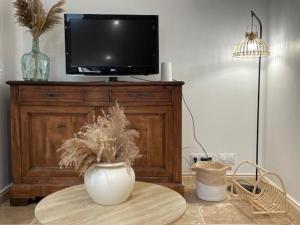 a tv sitting on top of a wooden entertainment center at Maison splendide avec piscine in Ribérac