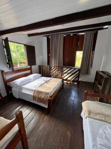a bedroom with two beds and two windows at Pousada Mandala em frente a Praia da Concha in Itacaré