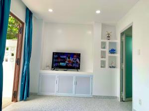 a living room with a tv on a white wall at NẮNG Homestay - Làng Chài Mũi Né - Mui Ne Fishing Village in Mui Ne
