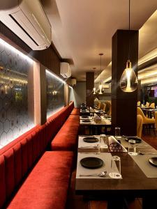 a restaurant with a long bar with red seats at INDUS TIARA- A Corporate Boutique Hotel in Siliguri